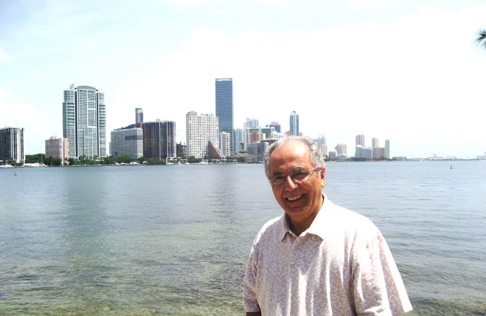 Smiling man standing by waterfront with skyline